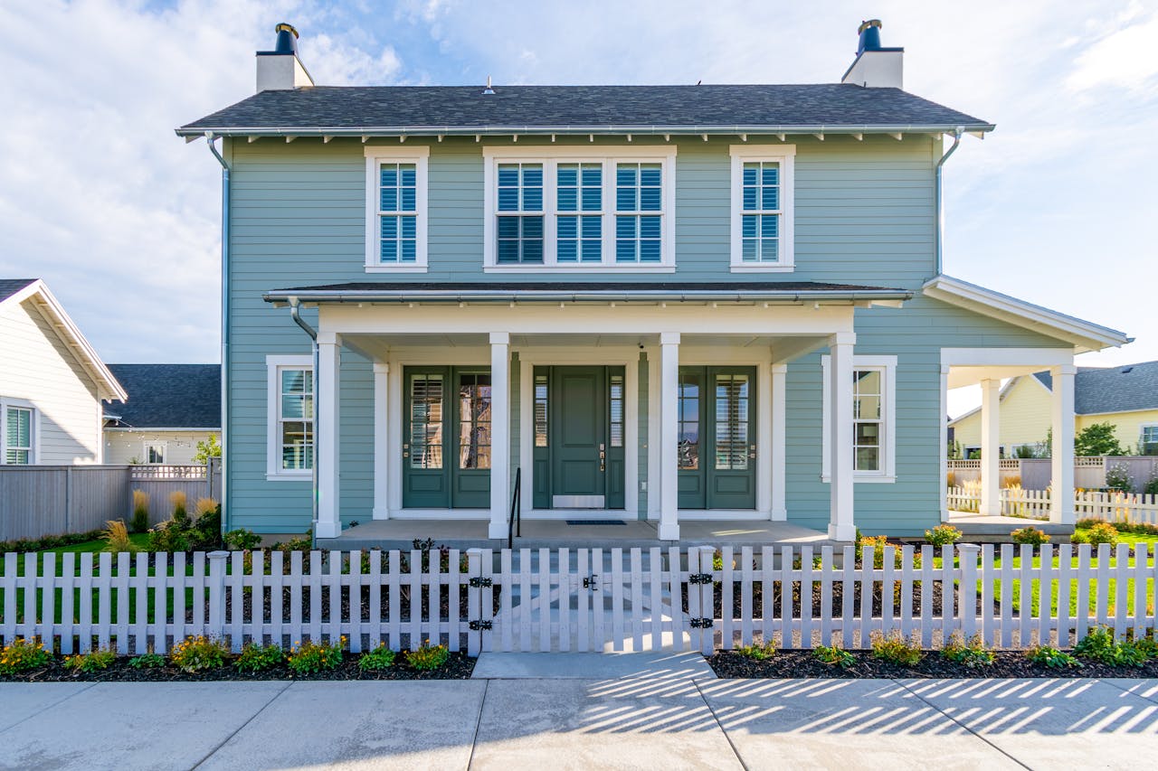 about-us A modern suburban house with a charming white picket fence in a quiet residential neighborhood.